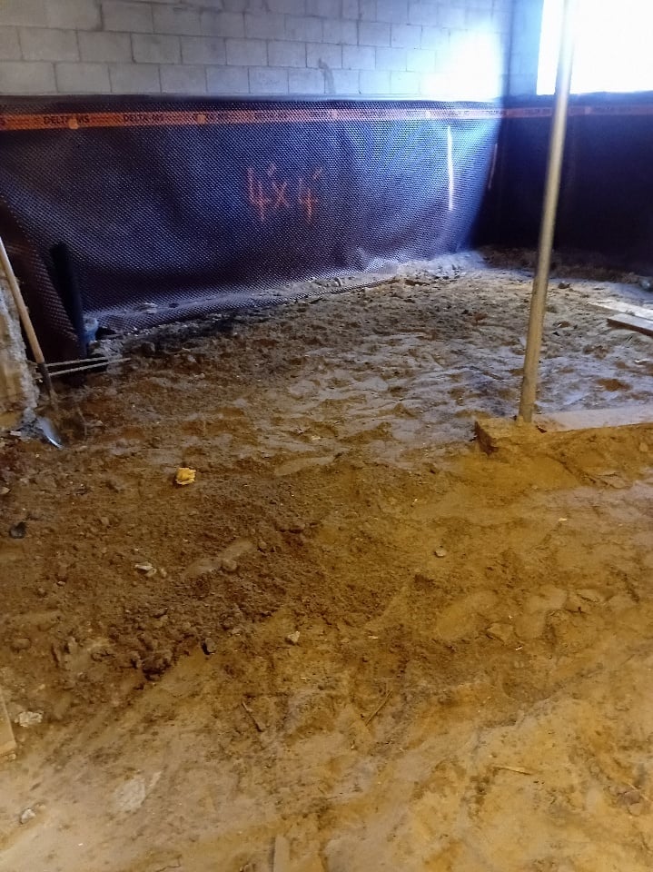 Horse stable interior with dirt floor, concrete block walls, and dark netting barrier with wooden posts