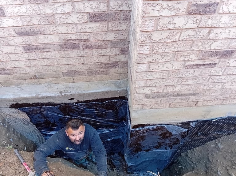 Man in blue clothing lying in a dark blue tarp or fabric between two brick walls